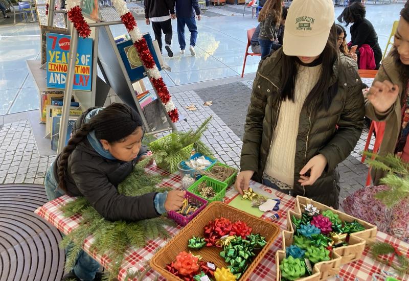 Young girl chooses decorations for a wreath. A table with different colored ribbons.